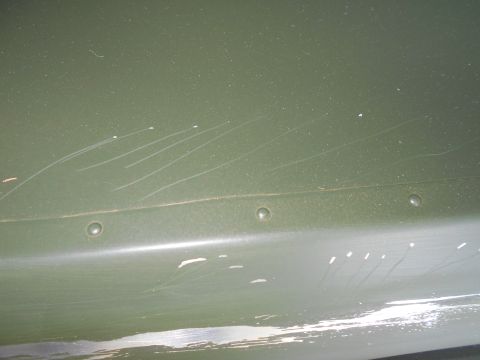 1992 Ford Bronco - Close-up of a scratched green painted metal panel with visible rivets.