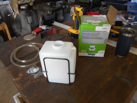 1992 Ford Bronco - A new coolant recovery kit is laid out with tools on a wooden workbench.