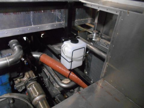 1992 Ford Bronco - Close-up view of an engine bay, showing a white coolant reservoir and orange flexible tubing.