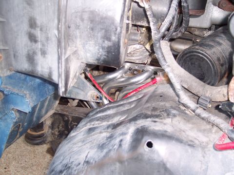 1990 Ford Bronco - Close-up view of the engine bay, focusing on the exhaust headers and associated wiring.