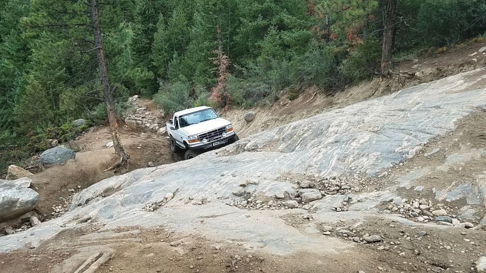 White Ford F-150 truck navigating a rocky, off-road trail
