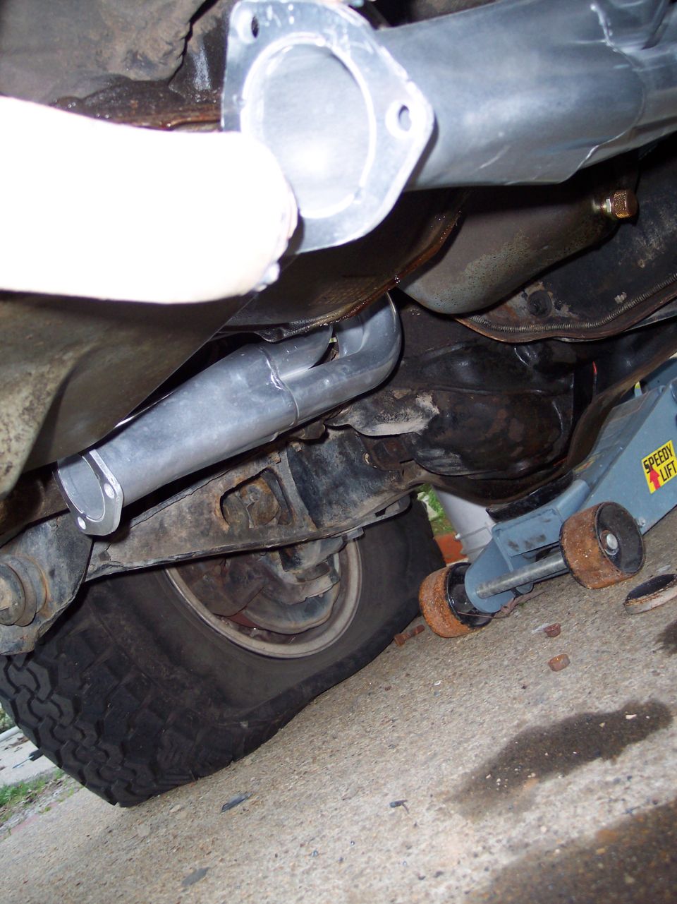 Underside of truck showing new bare metal exhaust Y-pipe and flange during install