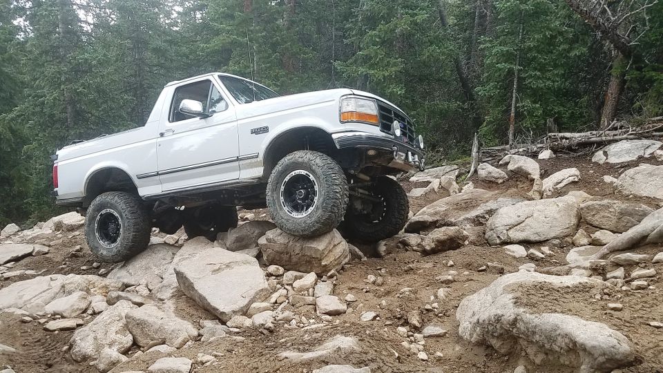 White 1995 Ford Bronco navigating a rocky off-road trail