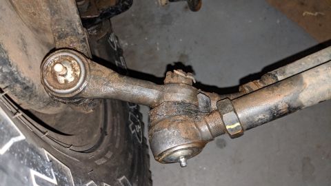 1995 Ford Bronco - Close-up of a corroded vehicle steering linkage assembly, showing wear and tear.