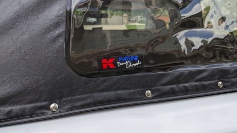 1995 Ford Bronco - A close-up view of a black soft top for a vehicle, featuring a clear window with a "Kayline Denver Colorado" logo. The soft top is attached…