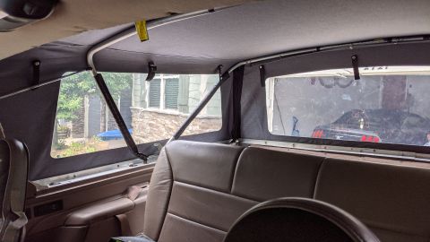 1995 Ford Bronco - Interior view of a 1995 Ford Bronco showing the rear seats and the soft top frame and windows. The windows show a residential exterior with…