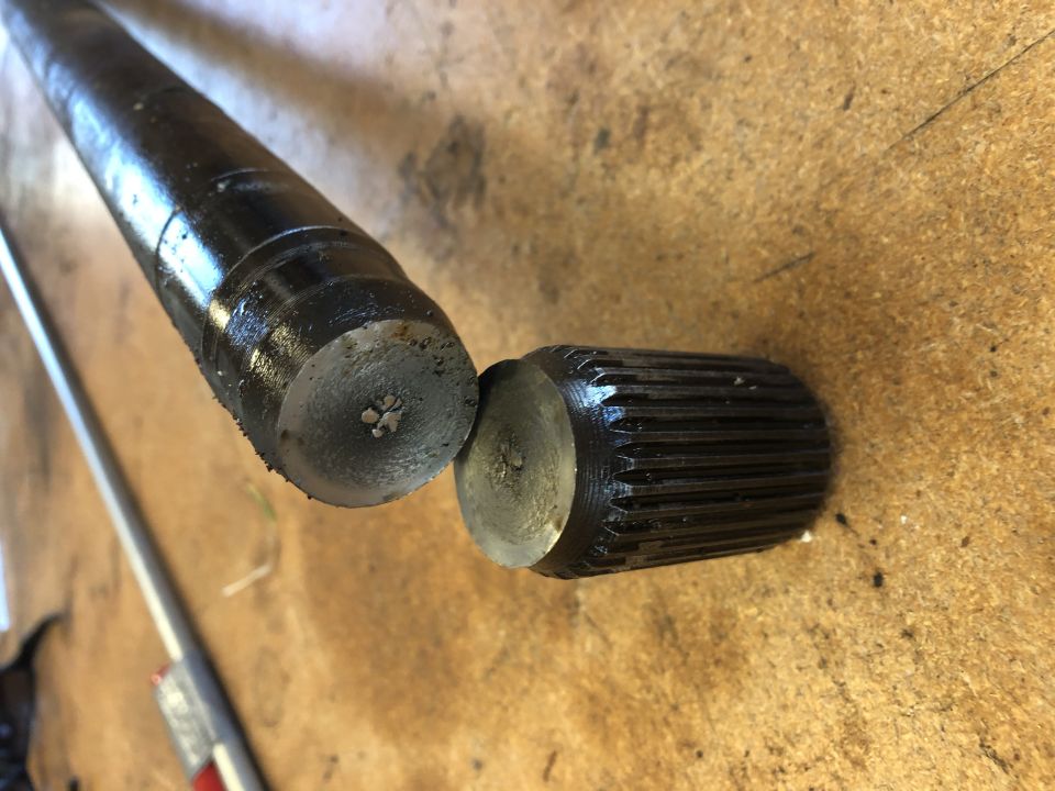 Two metal shafts, one with a splined end, on a wooden surface.