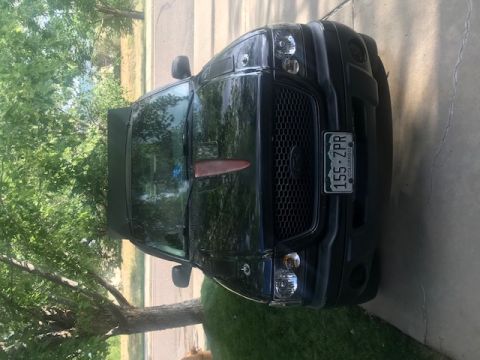 2000 Ford Explorer - Front view of a black Ford pickup truck parked in a driveway under a tree. The truck has a custom grille, aftermarket headlights, and a roo…
