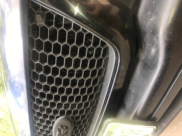 Black Ford Explorer grille with honeycomb pattern and a license plate.