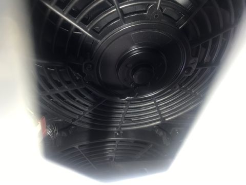 2000 Ford Explorer - Two black electric cooling fans are mounted side-by-side. The fans are viewed from a low angle, with bright light reflecting off the fan bl…