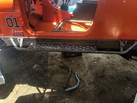 1992 Jeep Wrangler - The side view of an orange Jeep Wrangler shows custom metal side steps with a perforated metal tread plate. Visible text on the door reads…