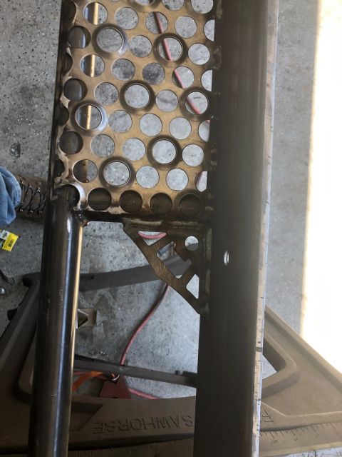 1992 Jeep Wrangler - A close-up view of a metal fabrication project, likely for a vehicle, showing a perforated metal sheet welded to a dark metal tube. A trian…