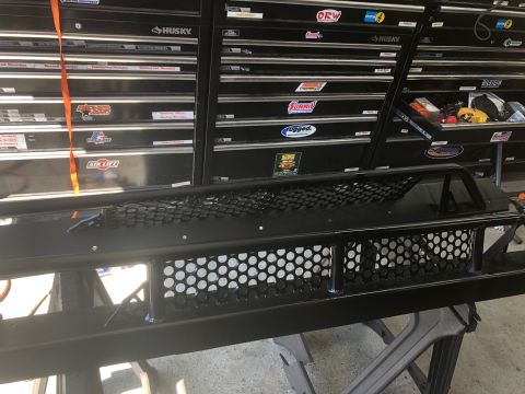 1992 Jeep Wrangler - A black custom aftermarket bumper with a honeycomb grille pattern sits in front of a black tool chest. The bumper has a tubular guard over…