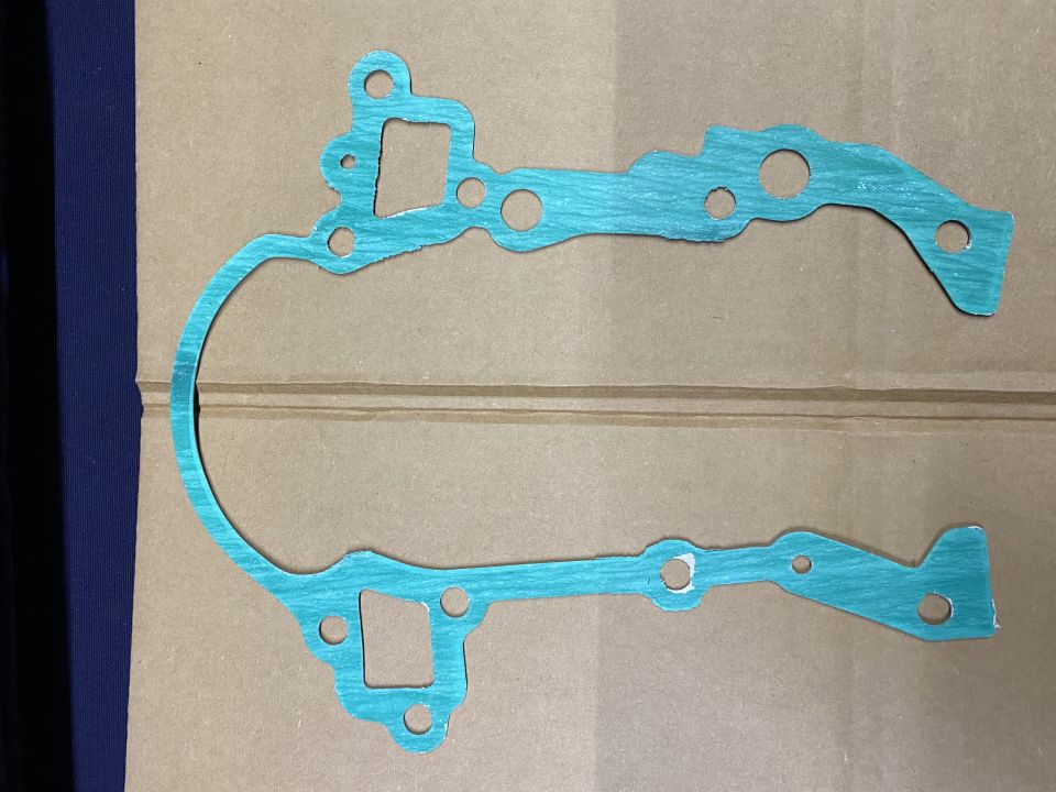 Teal gasket with holes on cardboard.
