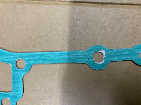 Teal gasket with circular cutouts on brown cardboard