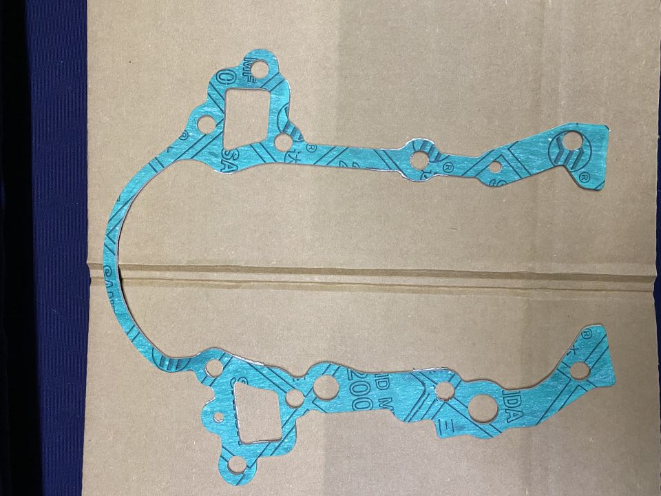 Teal gasket with holes and text on brown cardboard
