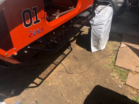 1992 Jeep Wrangler - Side view of an orange Jeep with custom graphics and side steps.