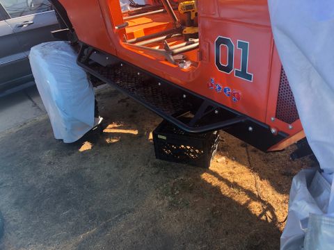 1992 Jeep Wrangler - This orange Jeep CJ-7, identifiable by its body style and "Jeep" badging, is partially covered and seen from the side.
