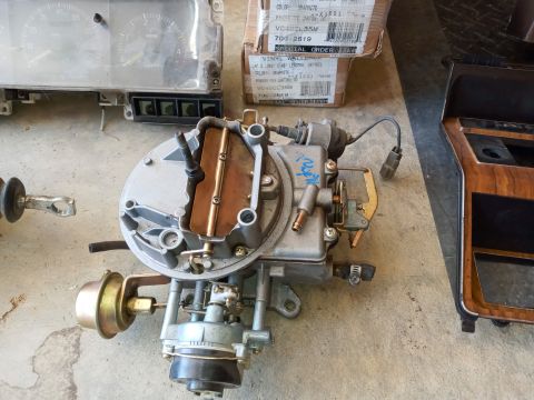 1994 Ford Bronco - Various automotive parts, including a carburetor and dashboard trim, are laid out on a concrete surface.