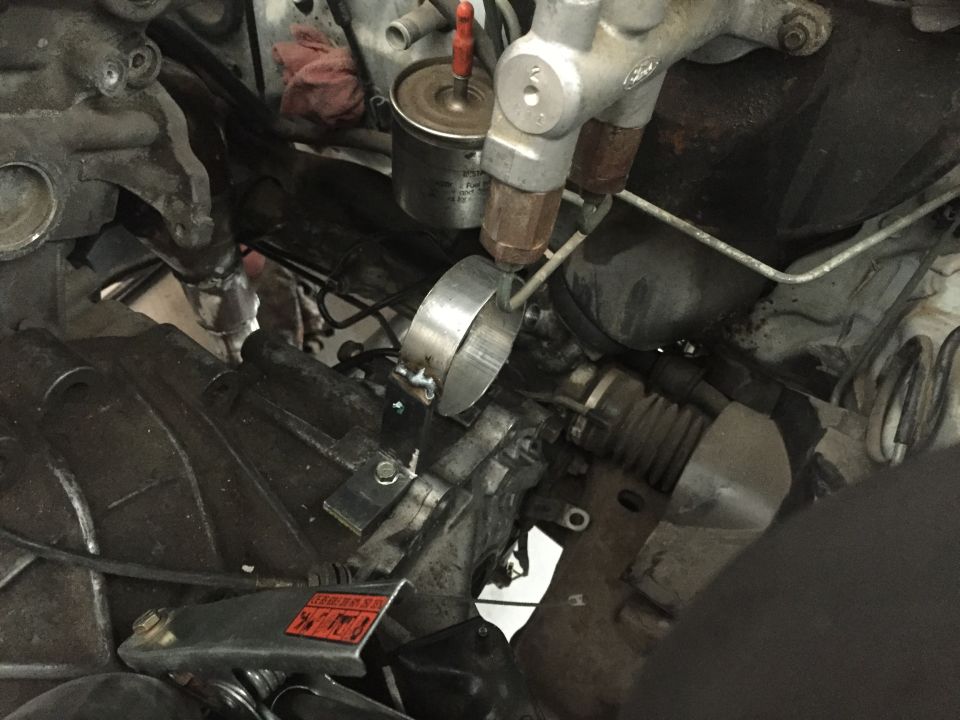 Close-up of engine bay with steering rack, brake lines, and fuel filter visible