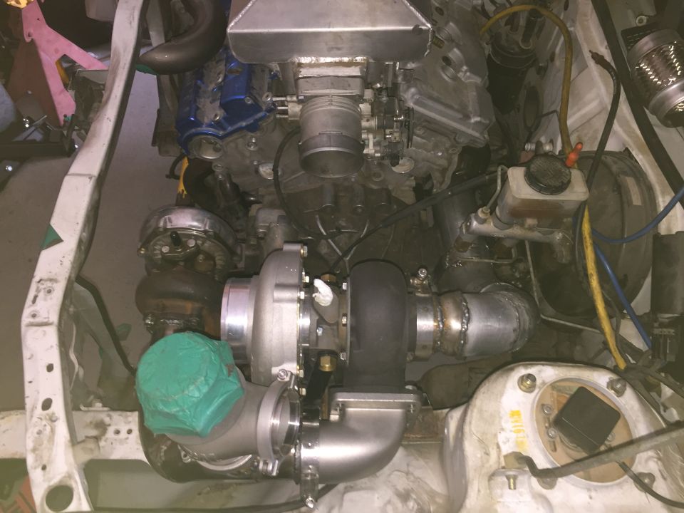 Engine bay with twin turbochargers and custom piping. Green cover on one turbo inlet