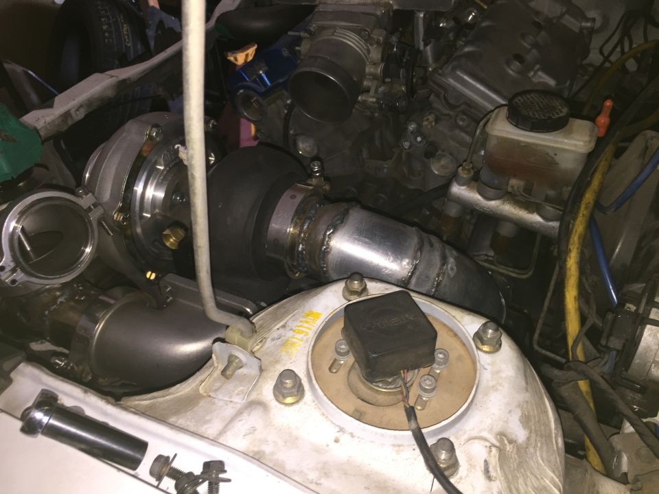 Engine bay with a turbocharger and intercooler piping installed. Brake fluid reservoir visible