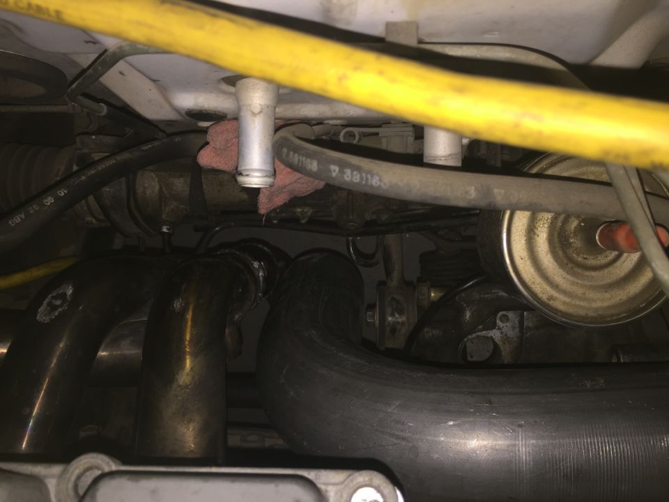 Engine bay with exhaust manifold and hoses visible, some text on a hose