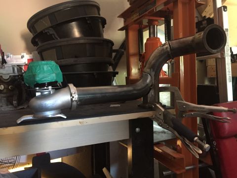 1993 Mercury Tracer - Custom exhaust pipe and turbocharger assembly held by clamps on a workbench.