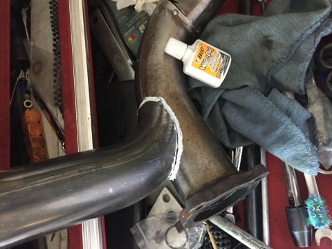 1993 Mercury Tracer - A close-up view of an exhaust pipe section, a bottle of quick-drying adhesive, and various tools are arranged in a toolbox.