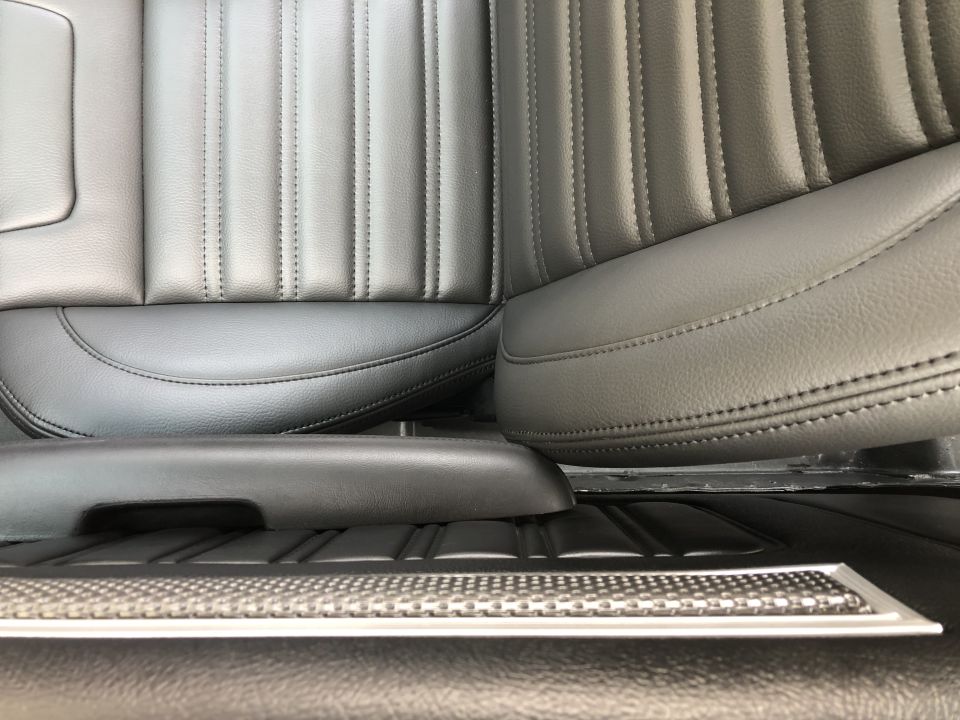 Black leather bucket seats with vertical stitching and a center console