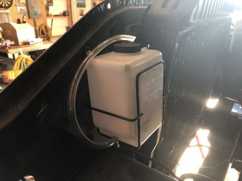 1978 Ford Bronco - Close-up of a windshield washer fluid reservoir with tubing, likely in a vehicle's engine bay.