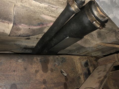 1978 Ford Bronco - The underside of a vehicle shows a fuel filler neck and hose assembly attached to the frame.