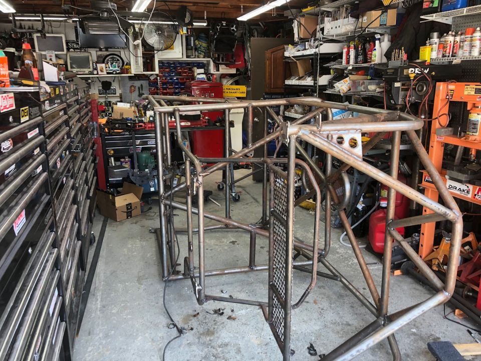 Bare metal custom roll cage frame in a garage workshop