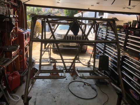 1992 Jeep Wrangler - A custom roll cage is being worked on in a garage, with a Jeep Grand Cherokee parked behind it.