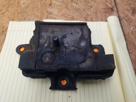 1979 Ford Bronco - A used engine mount, showing signs of wear and tear, is placed on a notepad for examination.