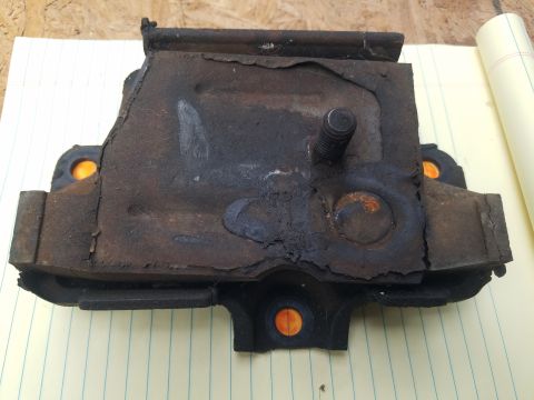 1979 Ford Bronco - A worn and corroded motor mount is shown against a background of lined paper.