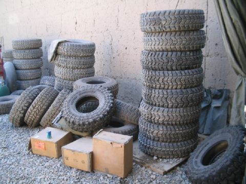 1981 Ford Bronco - Several stacks of off-road tires are visible, along with some cardboard boxes.