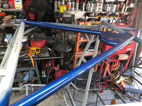1992 Jeep Wrangler - A custom roll cage, painted blue and gray, is shown in a cluttered garage setting with various tools and supplies visible.