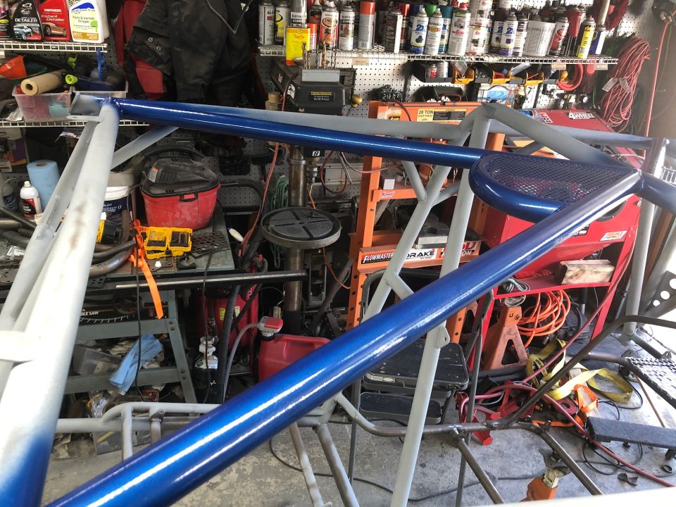Blue and gray roll cage in a garage with tools and shelves