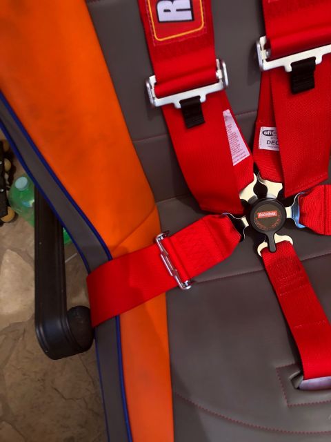 1992 Jeep Wrangler - Close-up of a racing seat a red 5-point harness and an orange side panel.