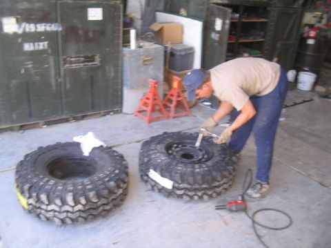 1981 Ford Bronco - A person is shown working on a tire in a garage setting with storage units in the background.