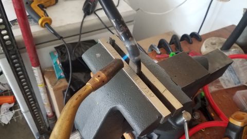 1985 Ford Bronco - Torch heating a metal rod clamped in a vise, with 'FULL JAW' marked on the vise.