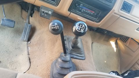 1985 Ford Bronco - The vehicle's interior shows a manual transmission shifter and a separate transfer case shifter for 4WD engagement.