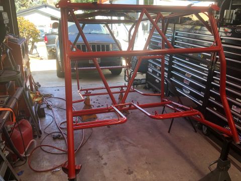 1992 Jeep Wrangler - A red roll cage is shown in a garage setting, with a Jeep SUV visible in the background.