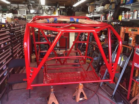 1992 Jeep Wrangler - A custom red roll cage is mounted on jack stands, ready for installation in a workshop environment.