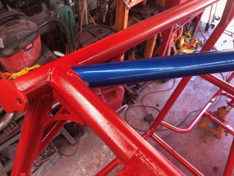 1992 Jeep Wrangler - A newly painted roll cage, red and blue bars, sits in a garage setting.