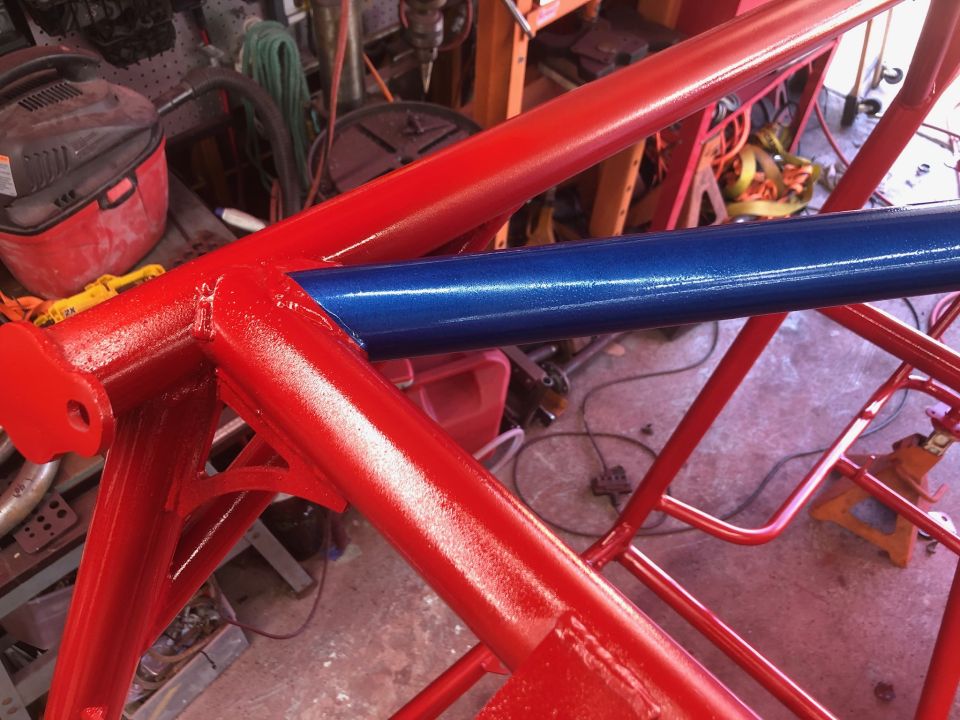 Close-up of a red and blue painted roll cage in a workshop