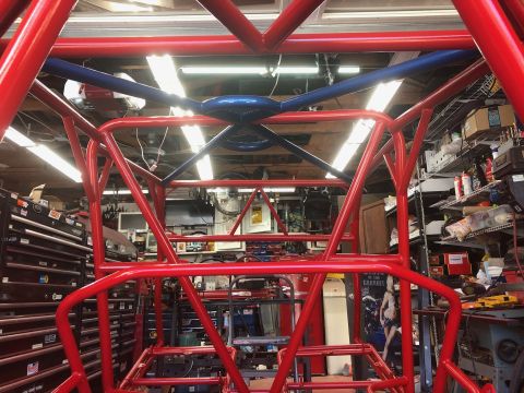 1992 Jeep Wrangler - A complex red and blue roll cage dominates the frame, suggesting a custom build in a cluttered garage setting.