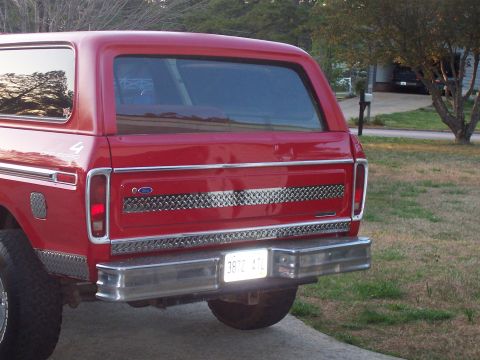 1979 Ford Bronco - The rear of a red Ford Bronco shows diamond plate trim and a license plate.