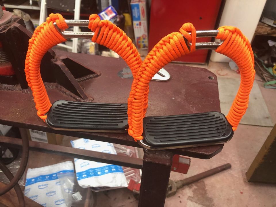 pair of orange paracord-wrapped grab handles with black rubber grips